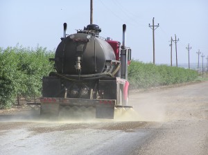 A truck applies magnesium chloride on a road along crops in the South Valley to capture moisture from the air for dust control. Photo courtesy of American Ag.