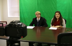 Mackenzie Mitchell and Jazmine Morfin are pictured recording a promotional video for the food drive. Through the use of a green screen, Mackenzie was able to integrate Hunger Games-style backgrounds for the version that was shown to students each week. 