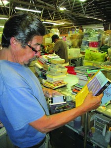 Michael Jollitt, the book pricer for the Visalia Rescue Mission’s thrift business, checks current pricing and rating for potential sale on a textbook, determining it should be considered for an Amazon listing. Nancy Vigran/Valley Voice